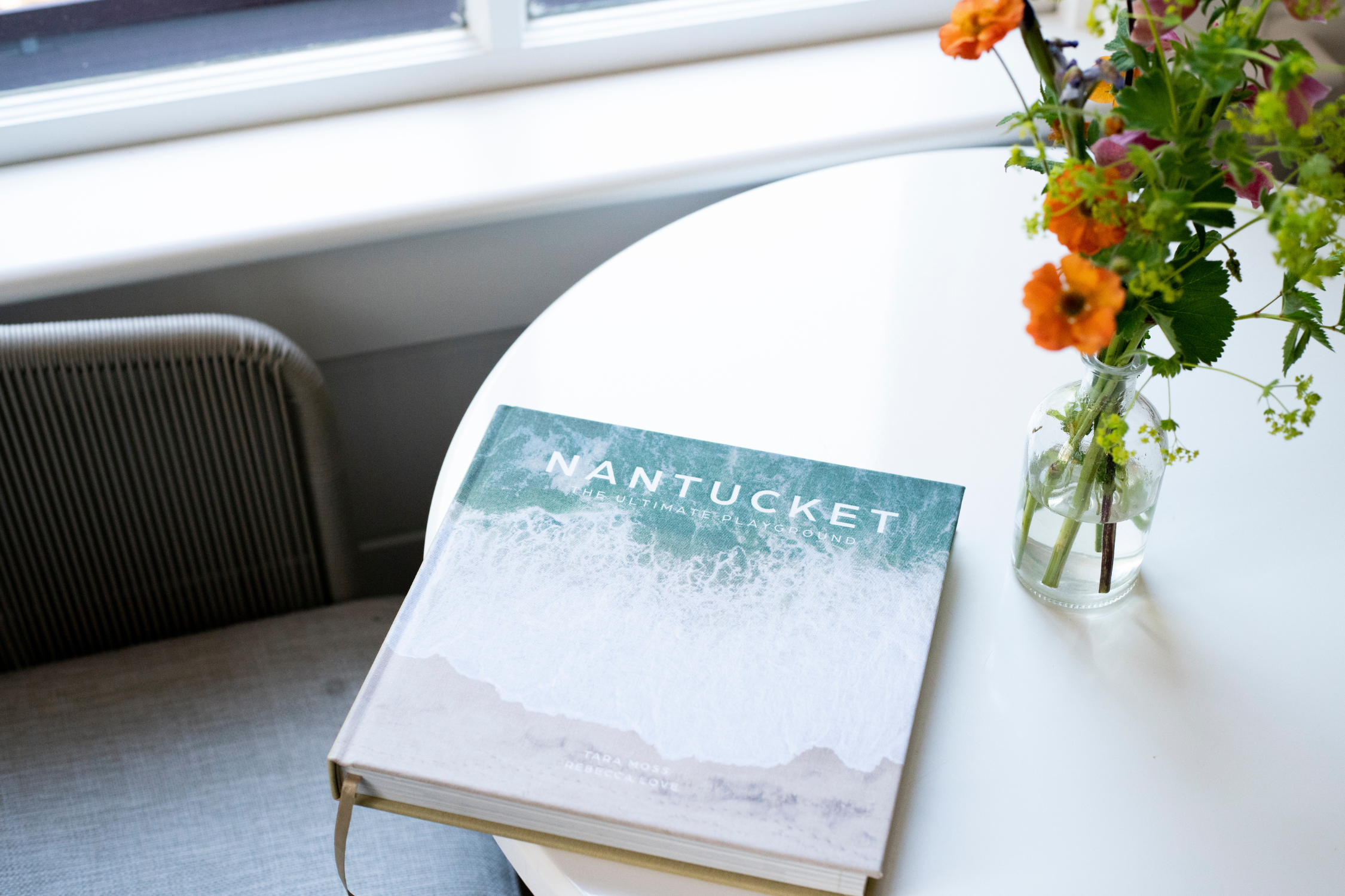 Nantucket book on a coffee table next to a vase of flowers