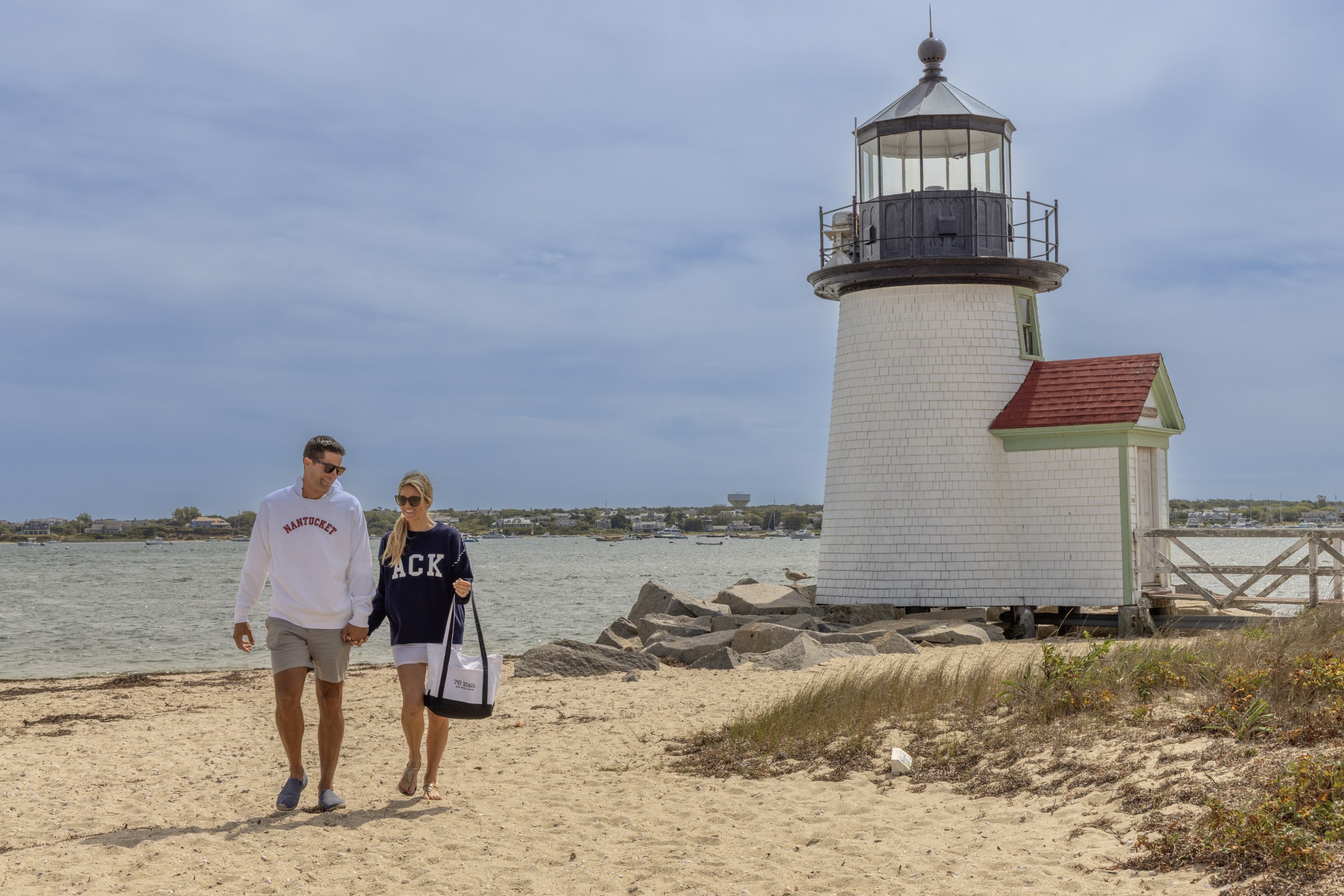 Couple walking on the beach in front of the Brant Lighthouse