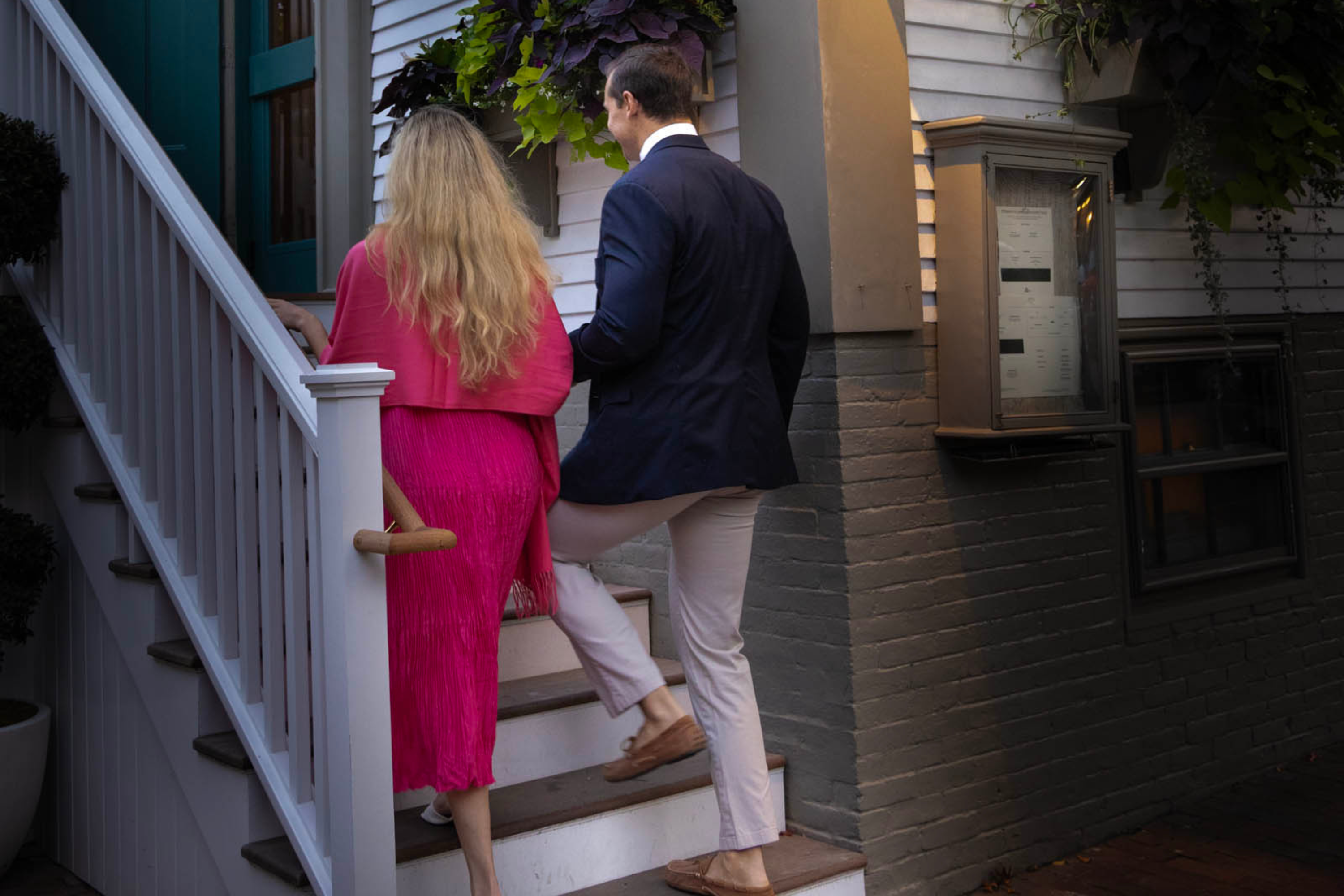 A dressed up couple walking into a Nantucket restaurant at night